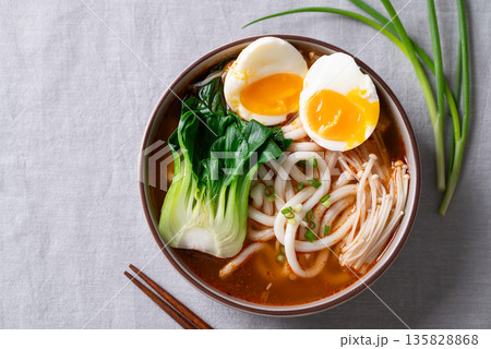 Top view of spicy Udon Noodle Soup topped with Bok Choy, Enoki Mushrooms and Soft Boiled Egg 135828868