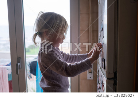 4-Year-Old Child Arranging Colorful Fridge Magnets. 135829027
