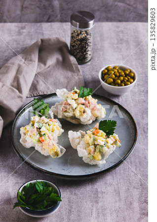 Olivier salad in rice paper bowls on a plate on the table vertical view Olivier salad in rice paper bowls on a plate on the table vertical view 135829603