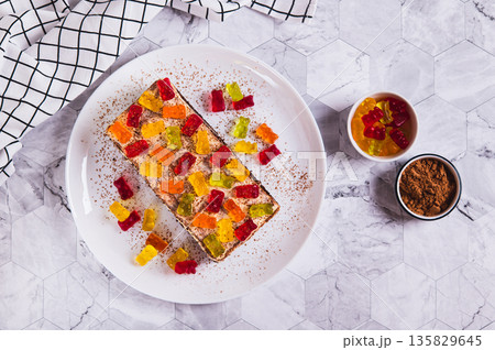 Chocolate cake decorated with gummy bears on a plate on a table top view 135829645
