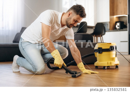 Cleaning the parquet. Male professional cleaning service worker is domestic room 135832581