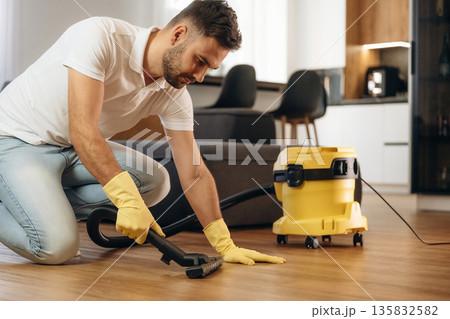Cleaning the parquet. Male professional cleaning service worker is domestic room 135832582