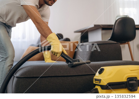 Sofa cleaning. Male professional cleaning service worker is domestic room 135832594