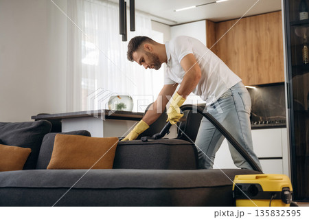 Sofa cleaning. Male professional cleaning service worker is domestic room Sofa cleaning. Male professional cleaning service worker is domestic room 135832595
