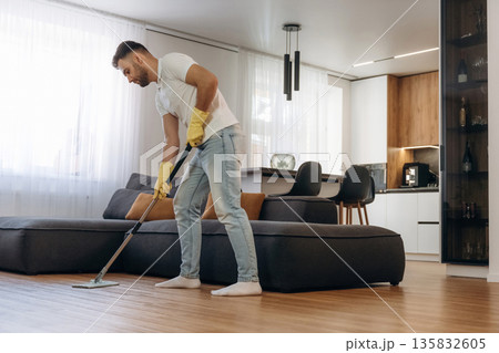 Wet cleaning of the floor. Male professional cleaning service worker is domestic room 135832605