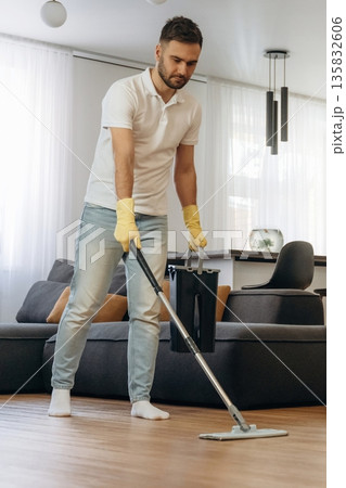 Wet cleaning of the floor. Male professional cleaning service worker is domestic room Wet cleaning of the floor. Male professional cleaning service worker is domestic room 135832606