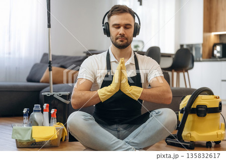 Doing yoga, meditation. Male professional cleaning service worker is domestic room 135832617