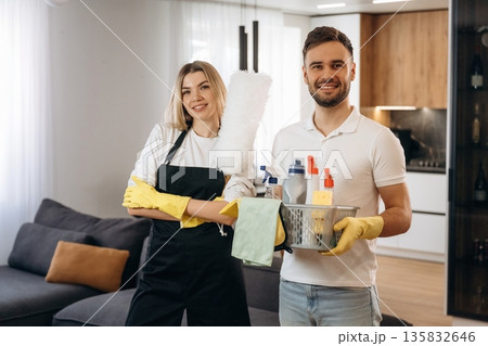 Woman is in uniform, standing. Two cleaning service workers are in domestic room Woman is in uniform, standing. Two cleaning service workers are in domestic room 135832646