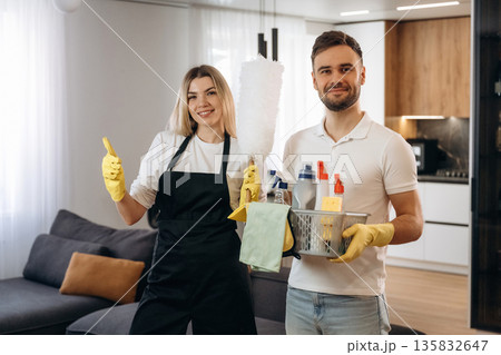 Woman is in uniform, standing. Two cleaning service workers are in domestic room 135832647