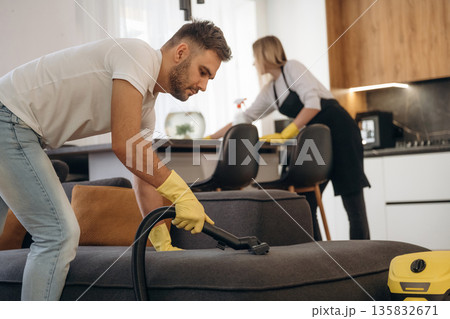 Taking care of sofa. Two cleaning service workers are in domestic room Taking care of sofa. Two cleaning service workers are in domestic room 135832671