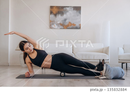 Yoga exercise. Woman with pug dog is at home Yoga exercise. Woman with pug dog is at home 135832884
