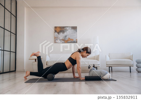 On the black mat, exercise. Woman with pug dog is doing yoga at home On the black mat, exercise. Woman with pug dog is doing yoga at home 135832911