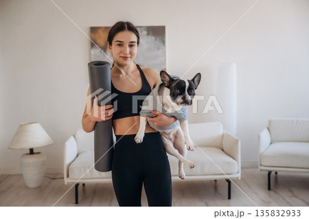 Sportive woman in yoga clothes is with pug dog at home Sportive woman in yoga clothes is with pug dog at home 135832933