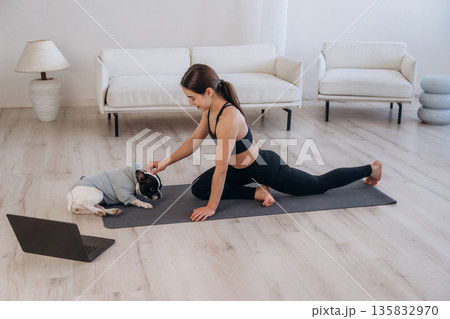Laptop is on the floor. Woman with pug dog is doing yoga at home Laptop is on the floor. Woman with pug dog is doing yoga at home 135832970