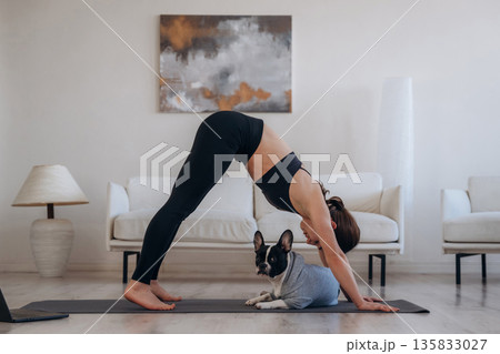 Active exercise. Woman with pug dog is doing yoga at home Active exercise. Woman with pug dog is doing yoga at home 135833027