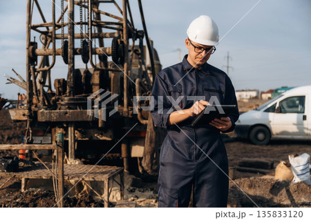 Vehicle is parked behind. Construction worker is near boring drilling machine Vehicle is parked behind. Construction worker is near boring drilling machine 135833120