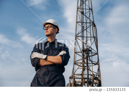 Standing with arms crossed. Construction worker is near boring drilling machine 135833135