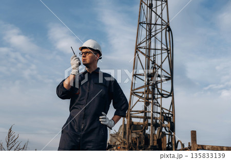 Talking by using walkie talkie. Construction worker is near boring drilling machine Talking by using walkie talkie. Construction worker is near boring drilling machine 135833139