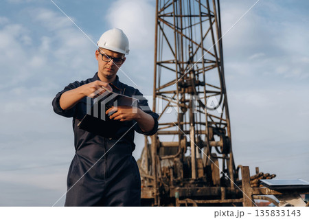 Documents in notepad. Construction worker is near boring drilling machine Documents in notepad. Construction worker is near boring drilling machine 135833143