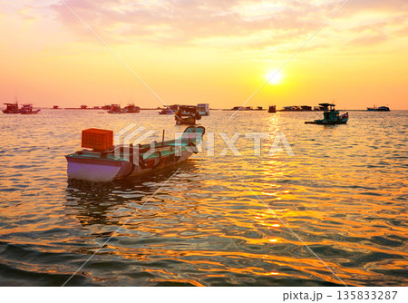 Fishing boats at shore on sunset. Fishermen's boats in sea at shore in fishing village Fishing boats at shore on sunset. Fishermen's boats in sea at shore in fishing village 135833287