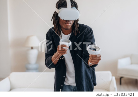 Focused on playing the game. Black man in virtual reality glasses at home 135833421
