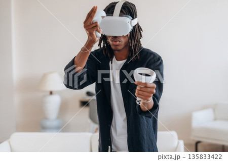 Focused on playing the game. Black man in virtual reality glasses at home Focused on playing the game. Black man in virtual reality glasses at home 135833422