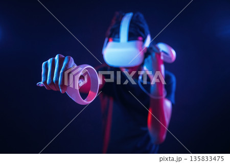 Making a punch, playing boxing game. African American guy is with virtual reality glasses in neon room 135833475