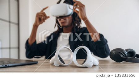 Ready for starting up. Young man is sitting by table with laptop and virtual reality glasses Ready for starting up. Young man is sitting by table with laptop and virtual reality glasses 135833656