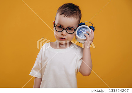 Time is running out, showing the clock. Cute little boy is against yellow background 135834207