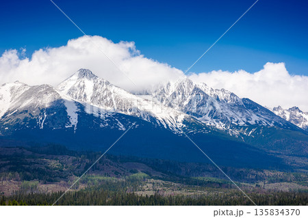 snow capped mountain peaks of high tatras in spring. scenic view of popular travel destination for remote trekking in slovakia, europe. alpine landscape with blue sky and clouds above the ridge snow capped mountain peaks of high tatras in spring. scenic view of popular travel destination for remote trekking in slovakia, europe. alpine landscape with blue sky and clouds above the ridge 135834370