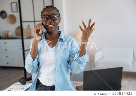Talking by phone. Woman is at home in domestic room Talking by phone. Woman is at home in domestic room 135834422