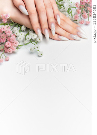 Woman's hands showing elegant white long nails with flowers 135834503