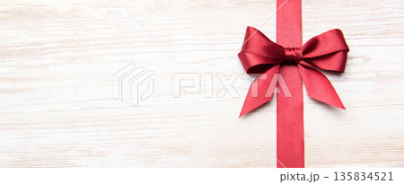 Red festive bow and ribbon on wooden background Red festive bow and ribbon on wooden background 135834521