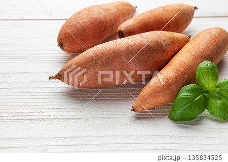Sweet potatoes and fresh basil on white wooden table Sweet potatoes and fresh basil on white wooden table 135834525