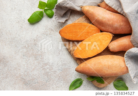 Sweet potatoes on cutting board with basil leaves 135834527