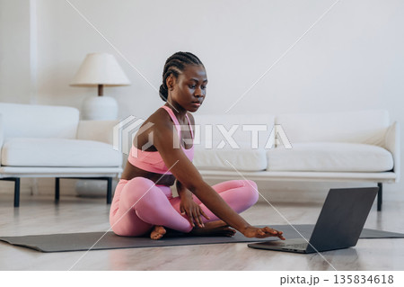 Taking online lessons by using laptop. Woman is doing yoga at home Taking online lessons by using laptop. Woman is doing yoga at home 135834618