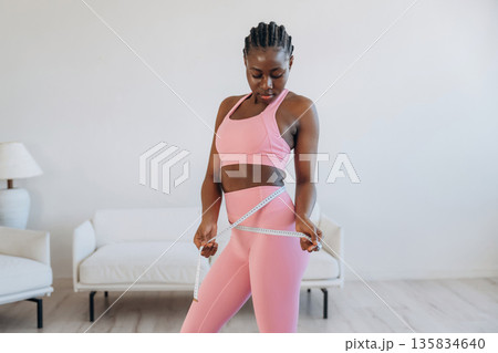 Measuring the waist, weight loss. Woman is doing yoga at home Measuring the waist, weight loss. Woman is doing yoga at home 135834640