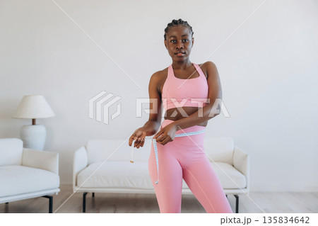 Measuring the waist, weight loss. Woman is doing yoga at home 135834642