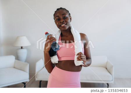 Bottle of water is in hand. Woman is doing yoga at home Bottle of water is in hand. Woman is doing yoga at home 135834653