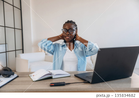 Black laptop is on the table. Woman is at home in domestic room Black laptop is on the table. Woman is at home in domestic room 135834682