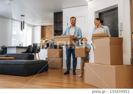 Bunch of boxes. Family of husband, wife and son are moving into new house Bunch of boxes. Family of husband, wife and son are moving into new house 135834951