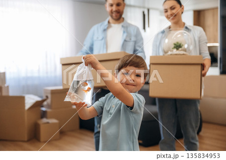 Boy is holding package with fish. Family of husband, wife and son are moving into new house Boy is holding package with fish. Family of husband, wife and son are moving into new house 135834953