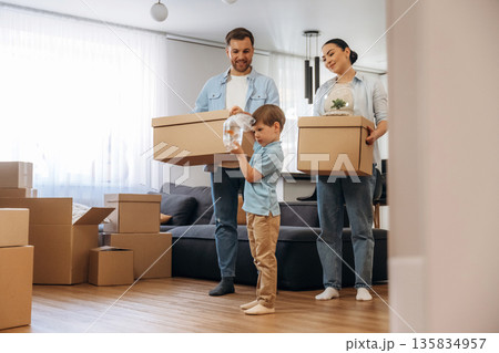Boy is holding package with fish. Family of husband, wife and son are moving into new house 135834957