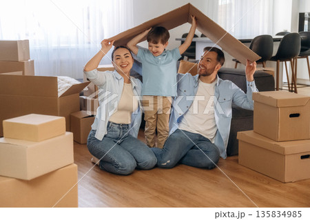 Playing with paper that is from the box. Family of husband, wife and son are moving into new house Playing with paper that is from the box. Family of husband, wife and son are moving into new house 135834985