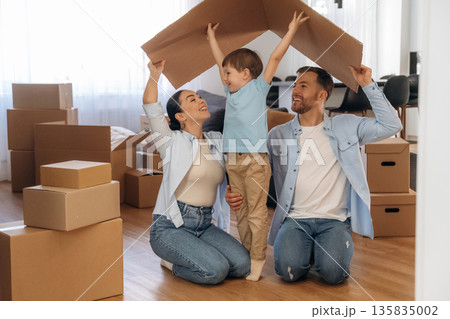 Conception of new home, under paper from box. Family of husband, wife and son are moving into new house Conception of new home, under paper from box. Family of husband, wife and son are moving into new house 135835002