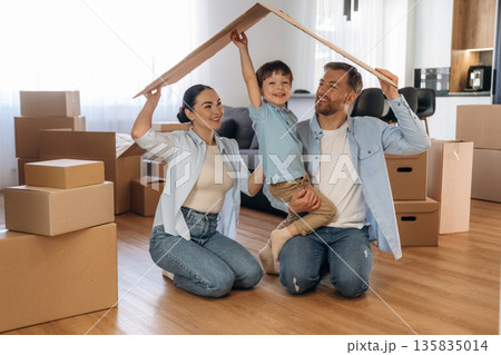 Positive facial expressions, paper from box. Family of husband, wife and son are moving into new house 135835014