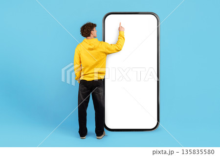Young guy touching screen of huge blank smartphone Young guy touching screen of huge blank smartphone 135835580