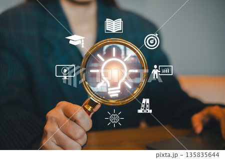 Businesswoman using magnifying glass with icons symbolizing innovation, strategy, and success in business. 135835644