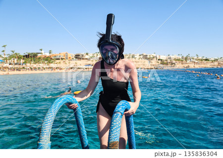 A woman overcomes her fear as she puts on a snorkel mask for the first time and dives into the water A woman overcomes her fear as she puts on a snorkel mask for the first time and dives into the water 135836304