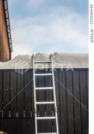 Ladder against a building for rooftop snow removal. 135836449